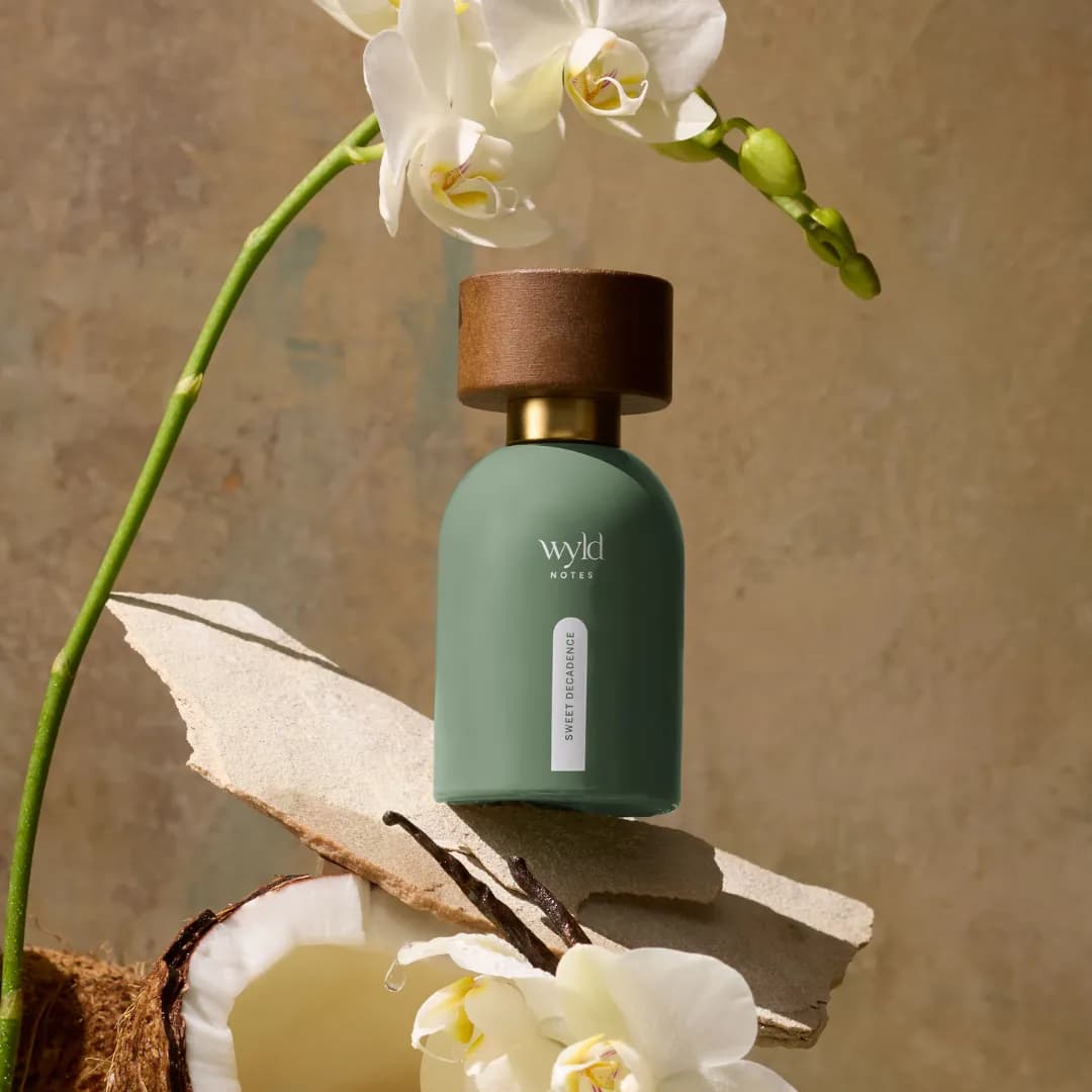 Sweet Decadence de Wyld Notes près d’une orchidée et d’une noix de coco ouverte