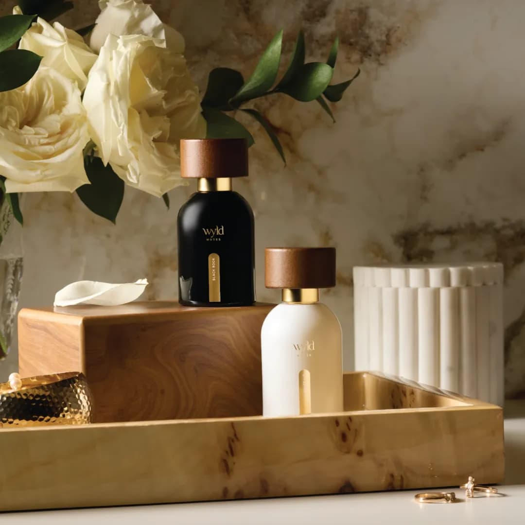 Le duo His & Hers : le flacon noir et le flacon blanc sur un plateau en bois